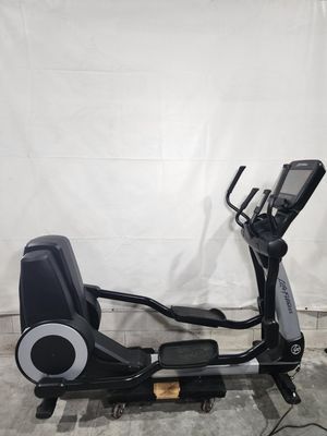 A black elliptical machine is sitting on top of a concrete floor.