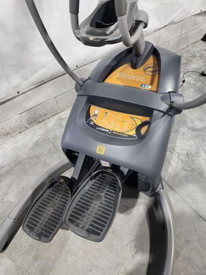 A gray and yellow elliptical machine is sitting on a concrete floor.