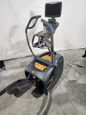 An elliptical machine is sitting on a concrete floor in a gym.