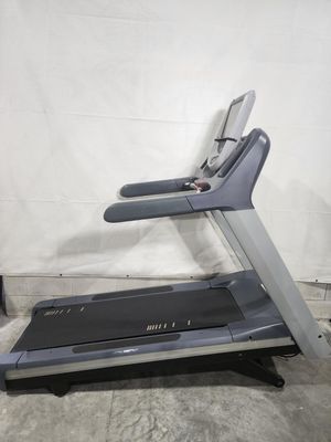 A treadmill is sitting on a concrete floor in front of a white wall.