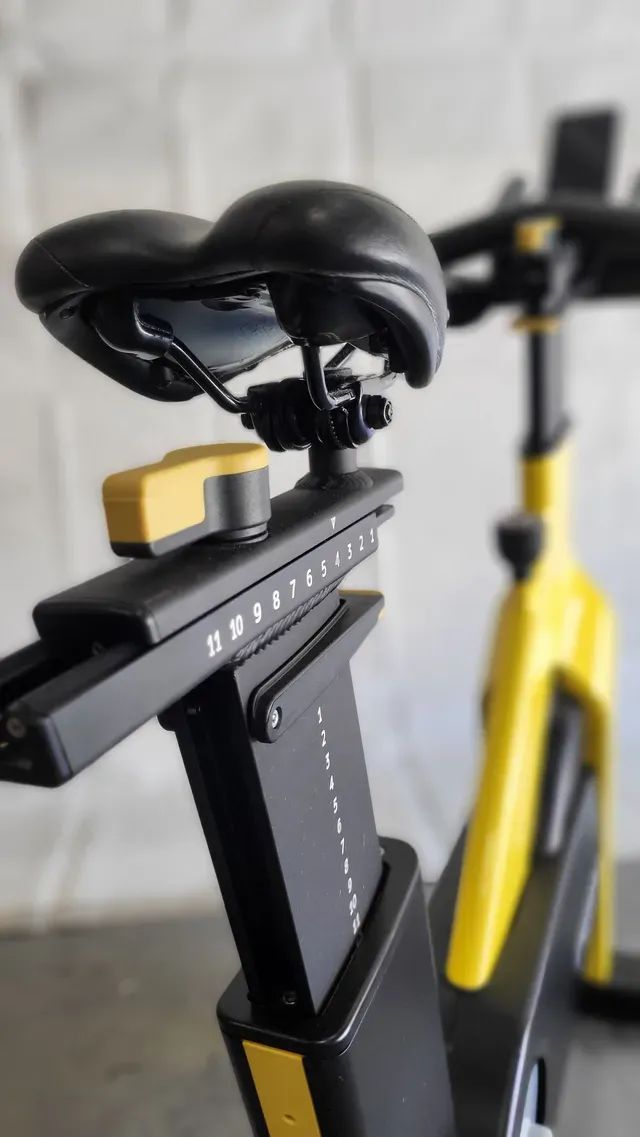 A yellow and black exercise bike is sitting on a table.