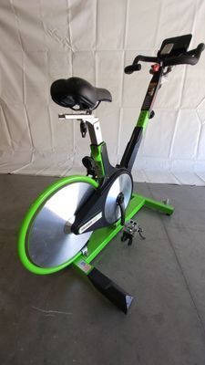 A green and silver exercise bike is sitting on a concrete floor.