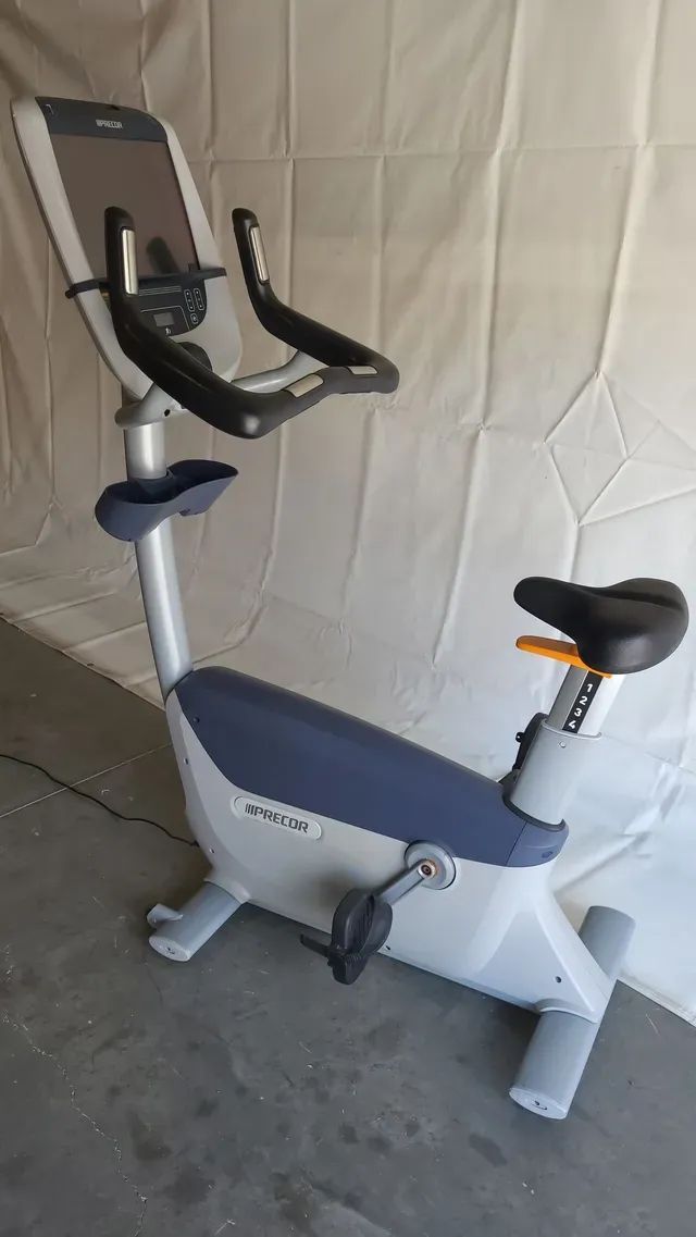 A white and blue exercise bike is sitting on a concrete floor.
