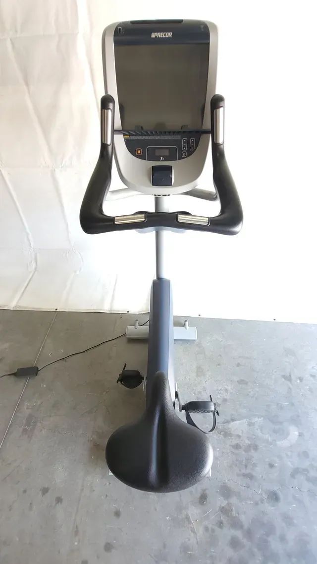 An exercise bike is sitting on a concrete floor in a garage.