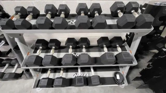 A bunch of dumbbells are stacked on top of each other on a rack.