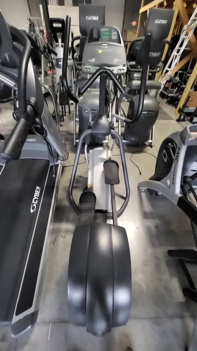 An elliptical machine is sitting in a gym next to a treadmill.