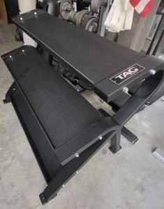 A black table with a bench underneath it in a gym.