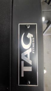A tag fitness logo is on the side of a gym machine.