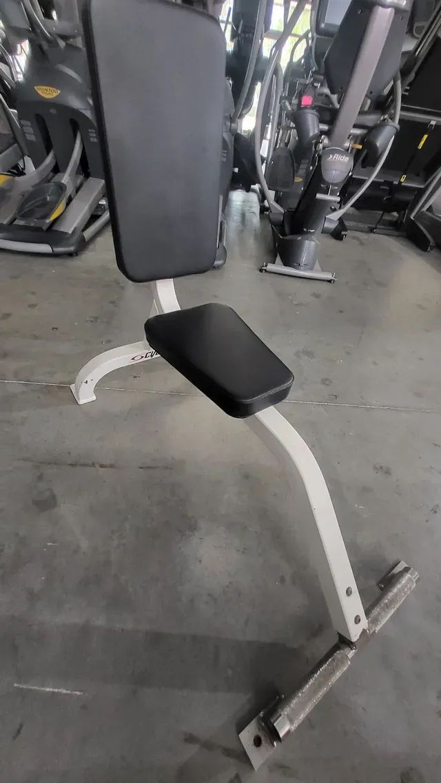 A black and white bench is sitting on a concrete floor in a gym.