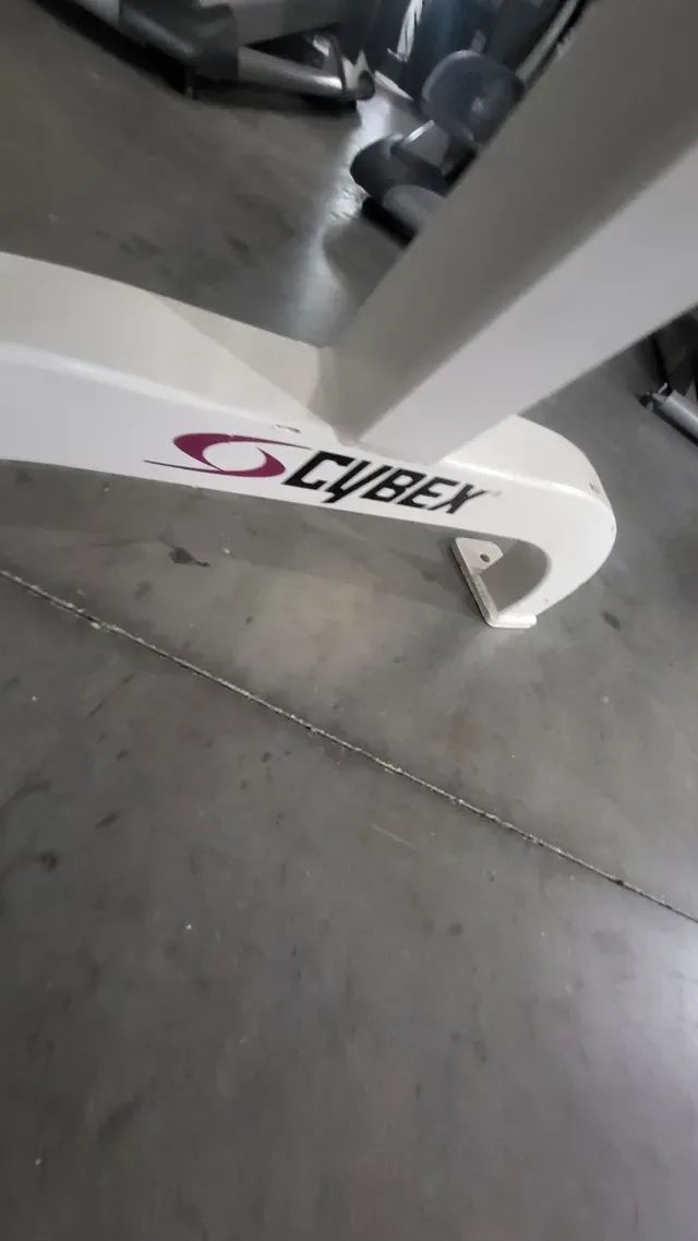 A cybex exercise bike is sitting on a concrete floor in a gym.