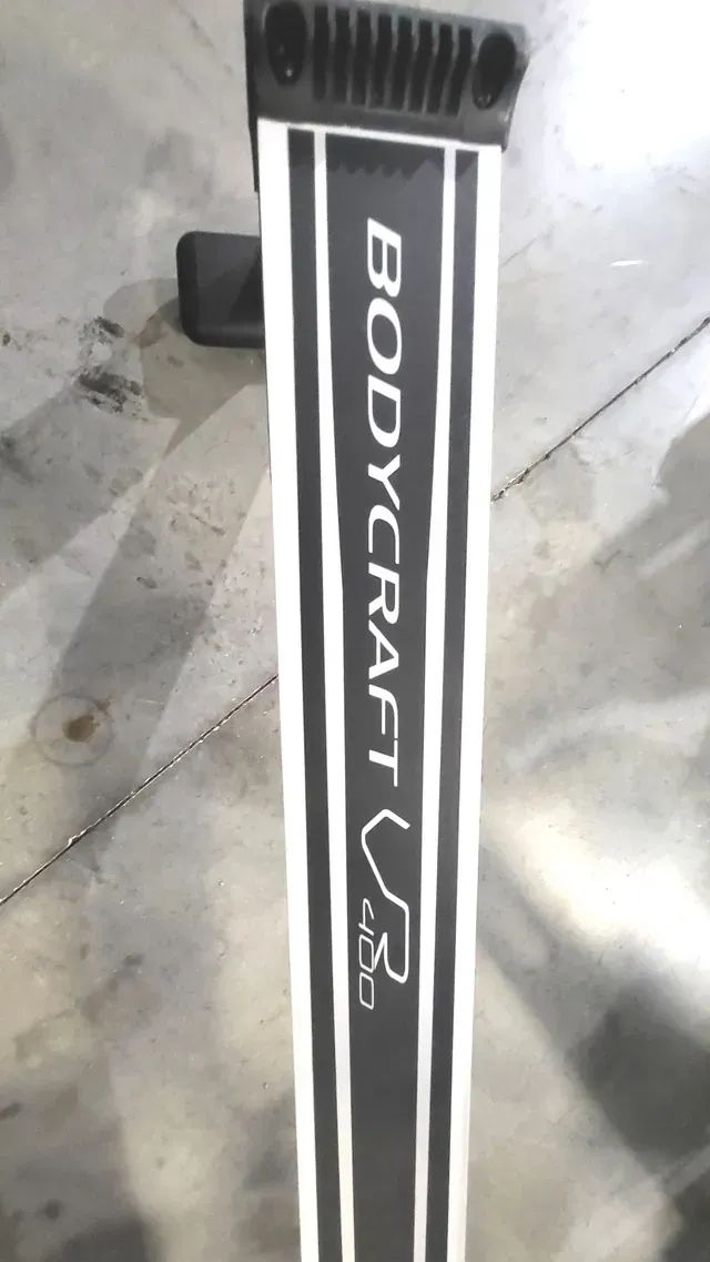 A bodycraft exercise machine is sitting on a concrete floor.