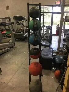 A row of medicine balls sitting on top of a rack in a gym.