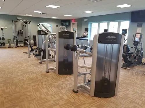 A large gym filled with lots of exercise equipment.