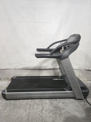 A treadmill is sitting on a concrete floor in front of a white wall.