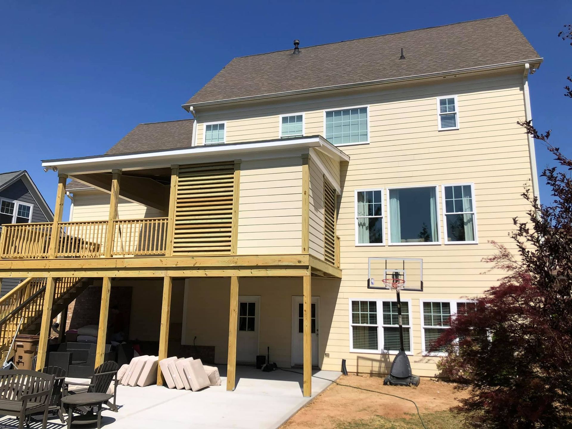 The back of a house with a large deck and a basketball hoop.