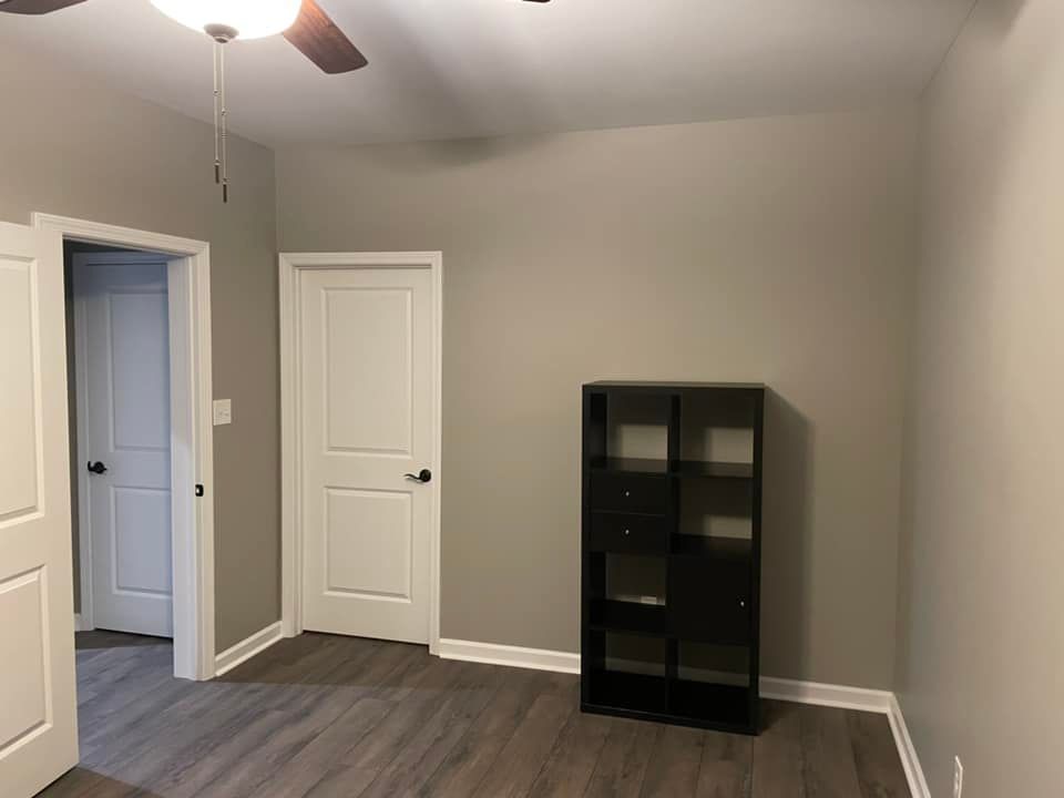 An empty room with a bookshelf and a ceiling fan.