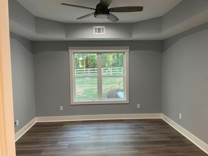 An empty room with a ceiling fan and a large window