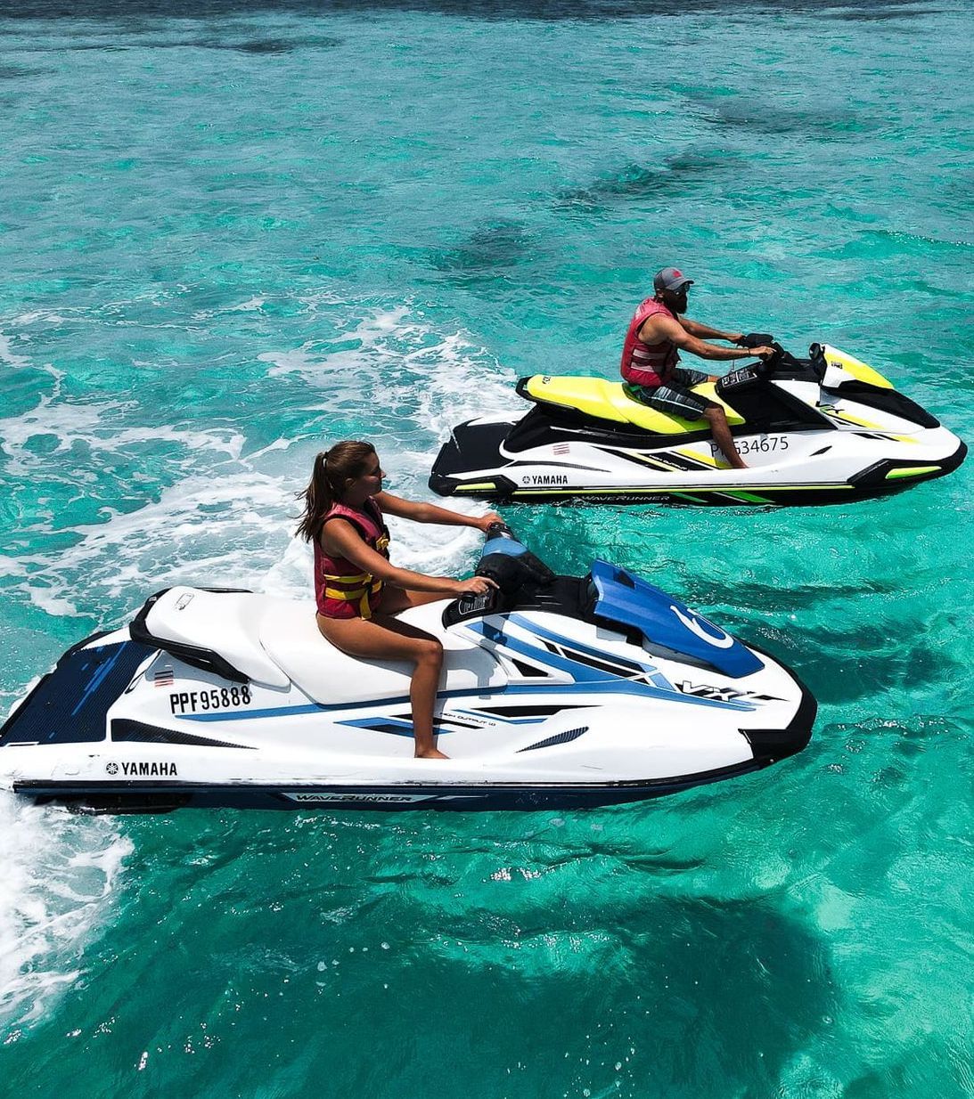 A man and a woman are riding jet skis in the ocean.