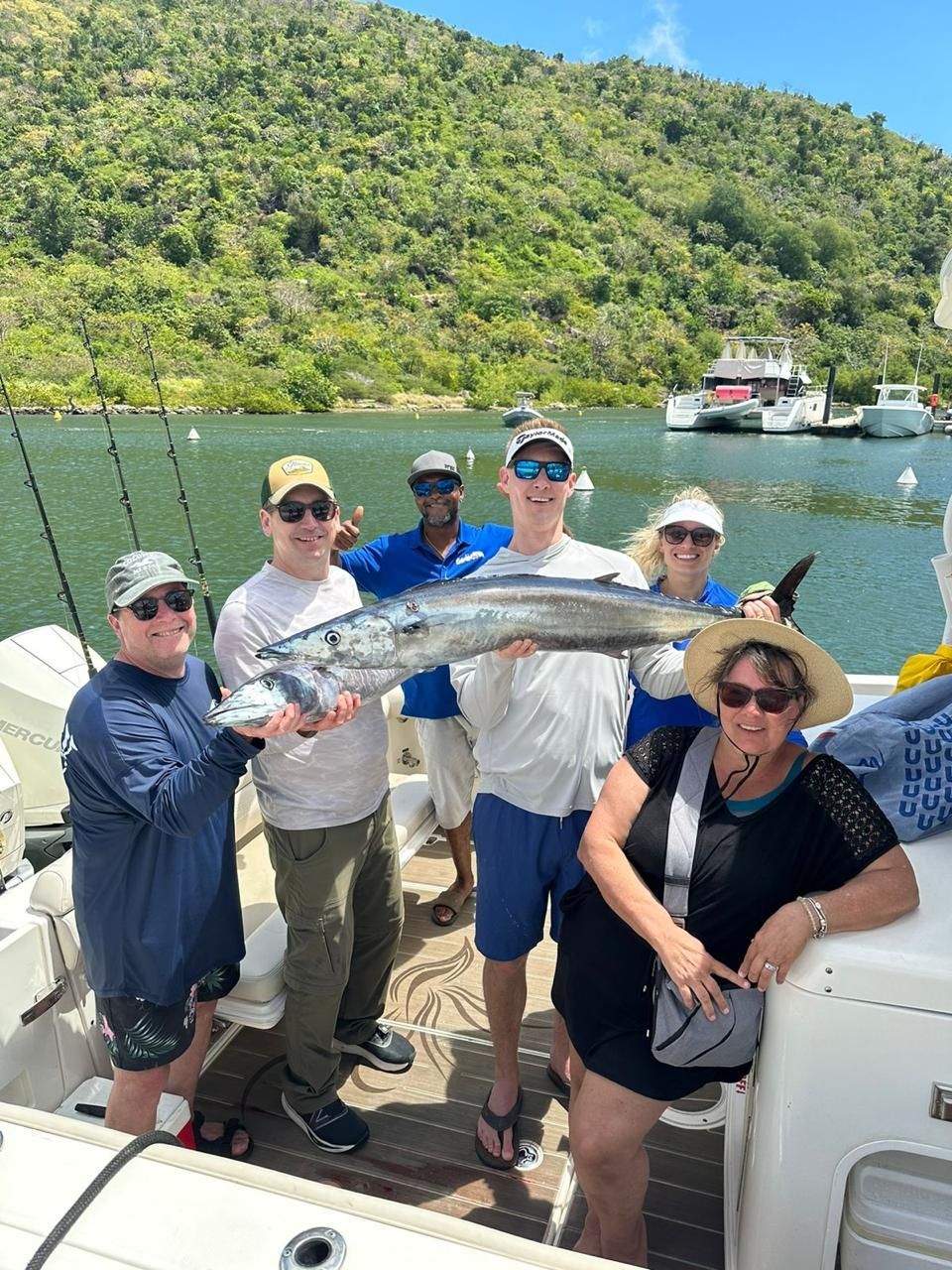 A group of people are standing on a boat holding a large fish.