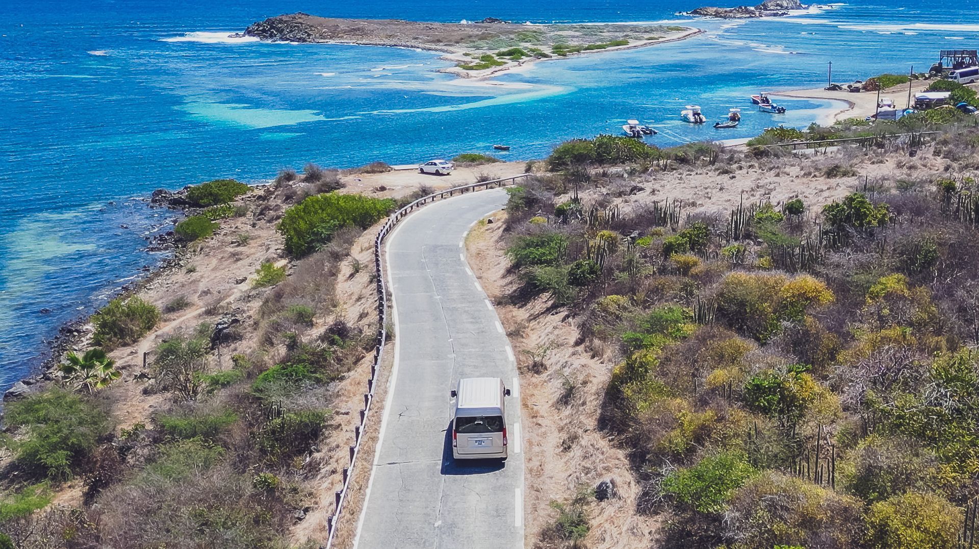 An aerial view of a small island in the middle of the ocean surrounded by mountains.