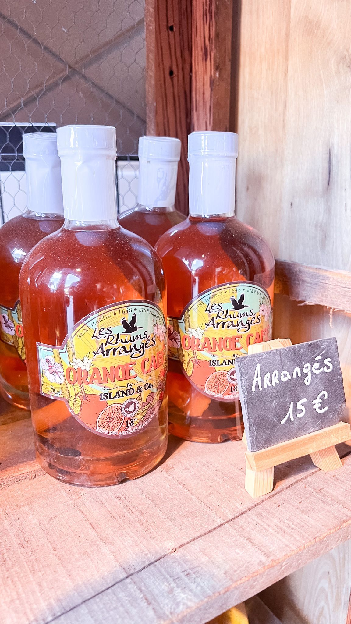 A row of bottles of alcohol are sitting on a wooden shelf.