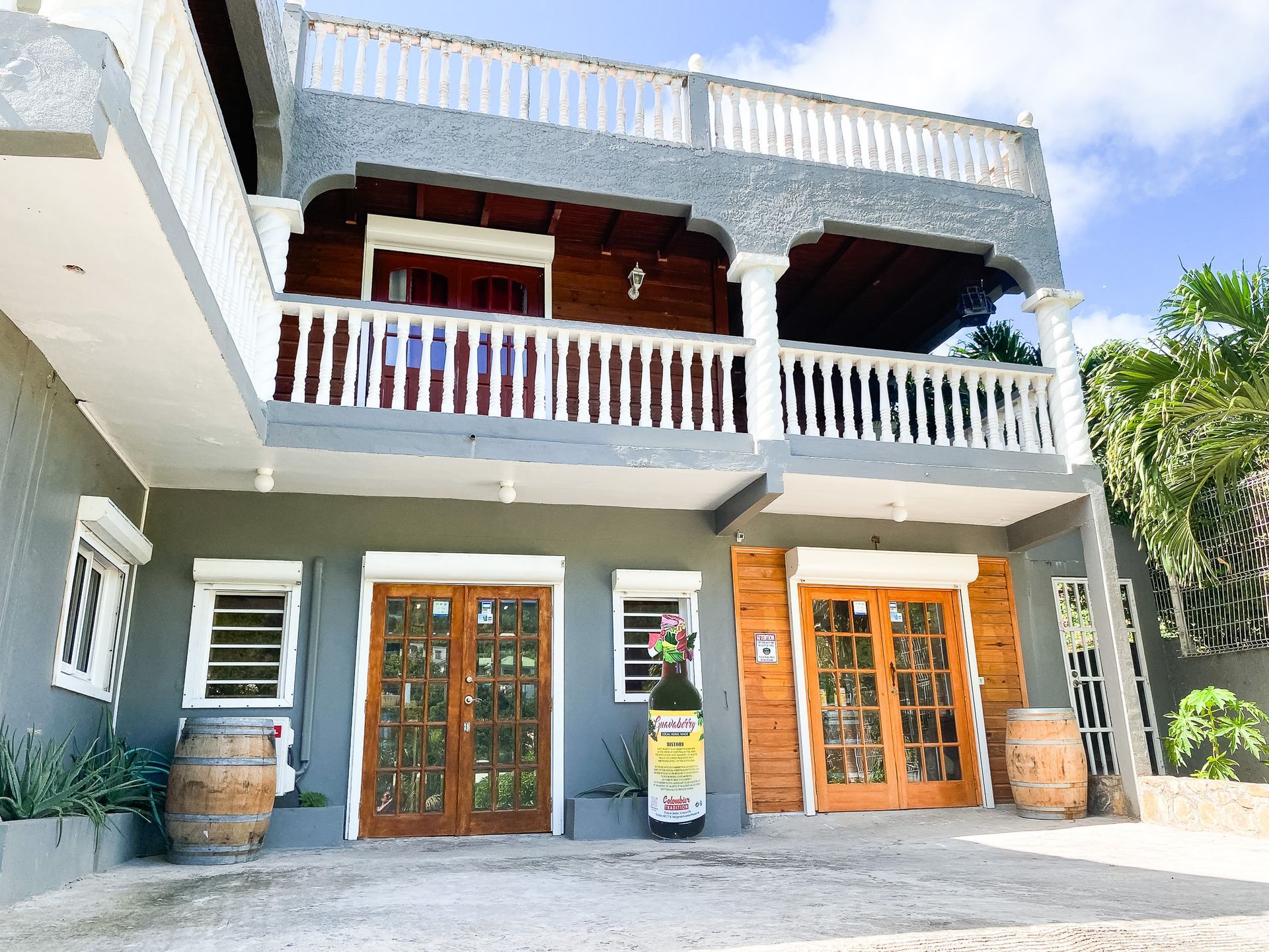 A large house with a balcony and a bottle of wine in front of it.