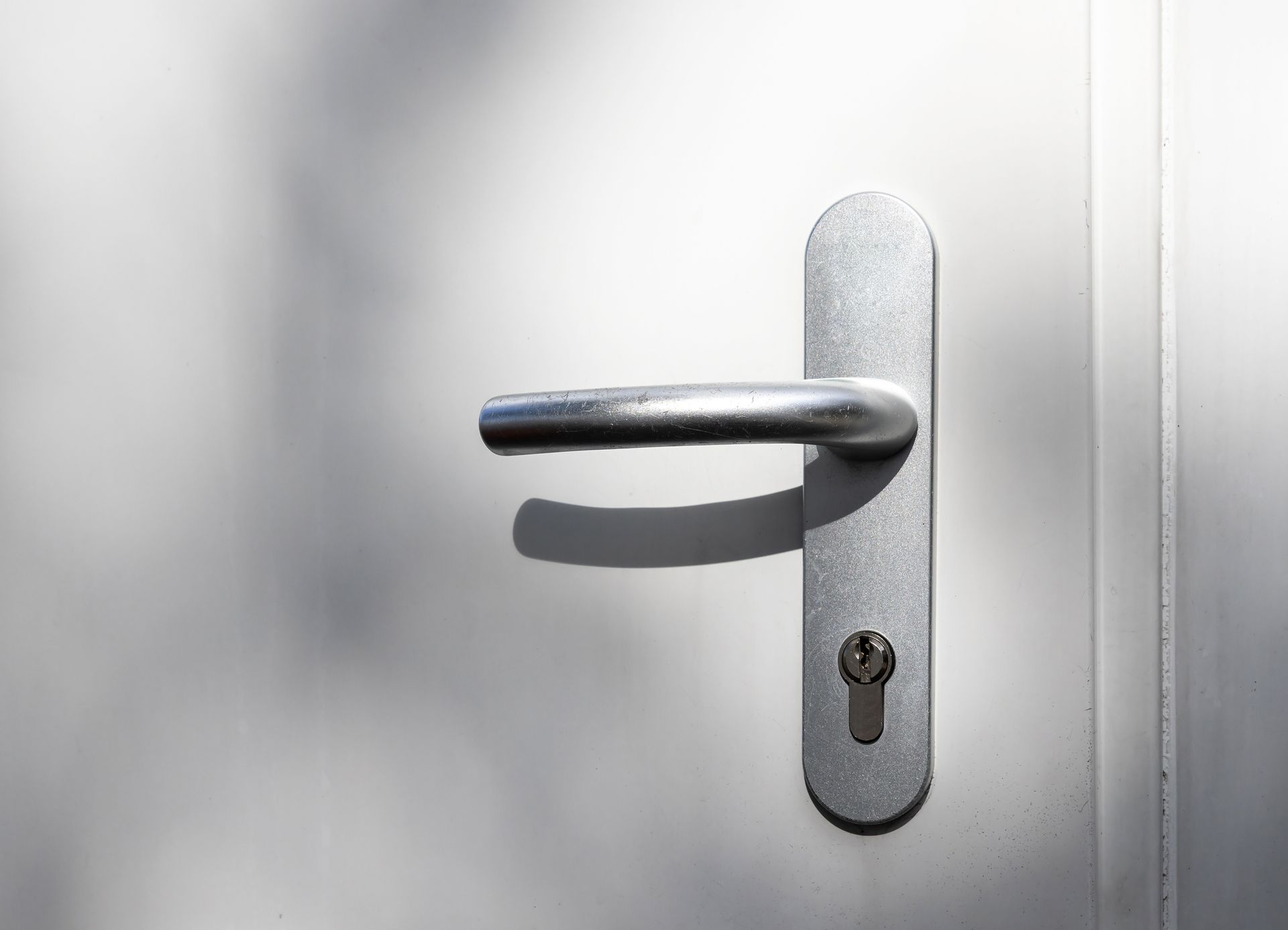 A close up of a door handle on a white door.