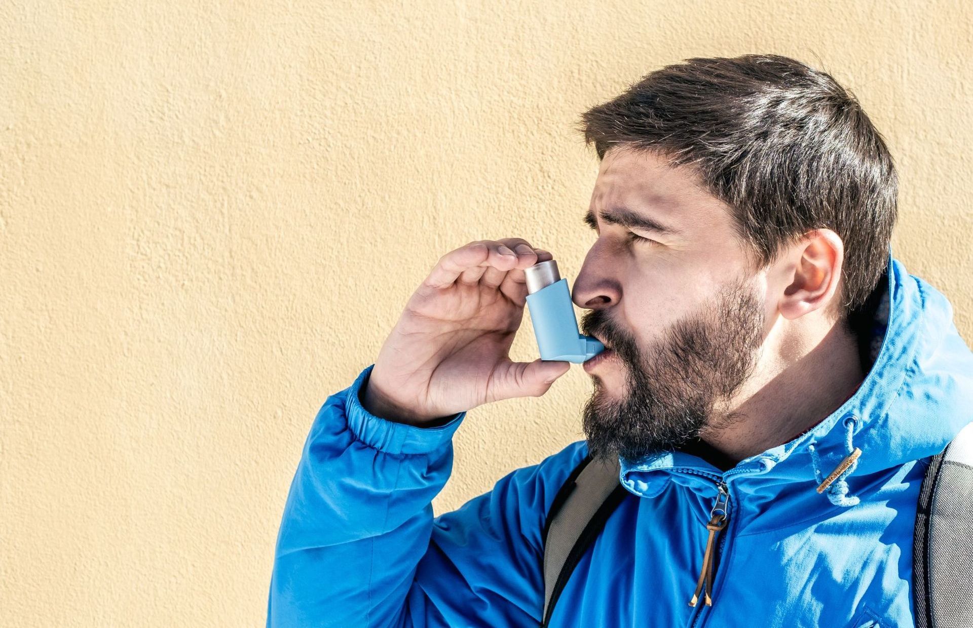 male hiker uses blue asthma inhaler