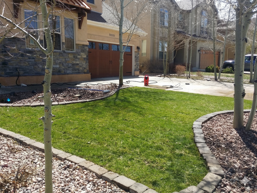 Courtyard with green lawn, stone edging, apartment buildings, and a red fire hydrant in the background