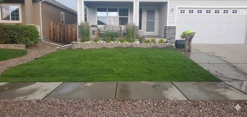 Single-story suburban house with a front lawn, stone walkway, and white garage