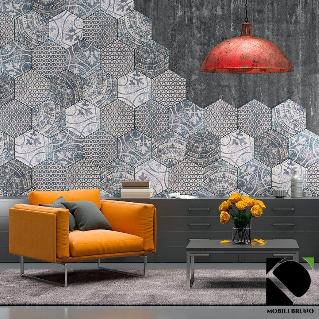 Poltrona arancione in un soggiorno moderno con parete decorata con piastrelle esagonali e lampada industriale rossa.