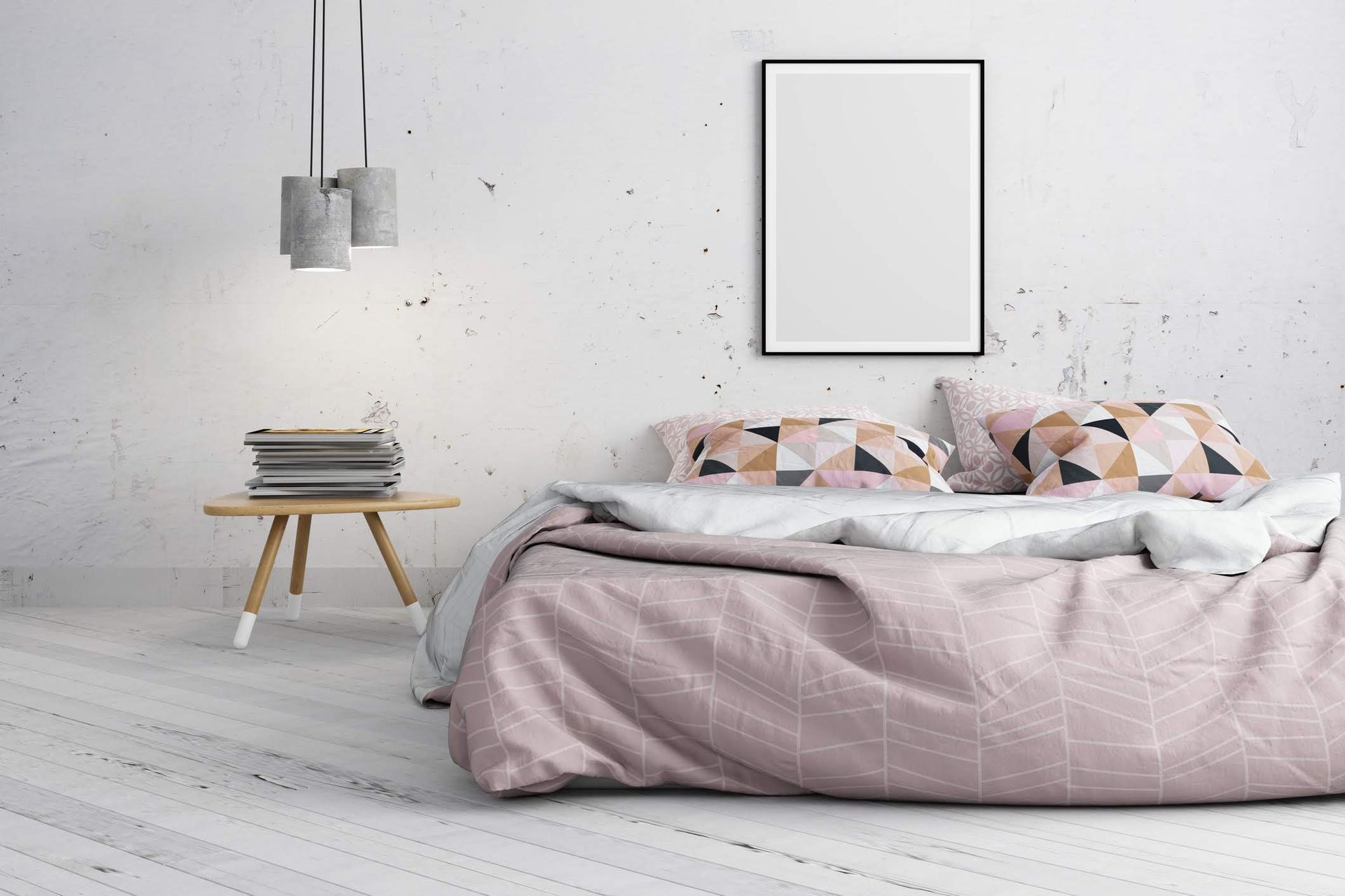 Camera da letto con letto, cuscini, coperta, tavolino con libri e opere d'arte alla parete.