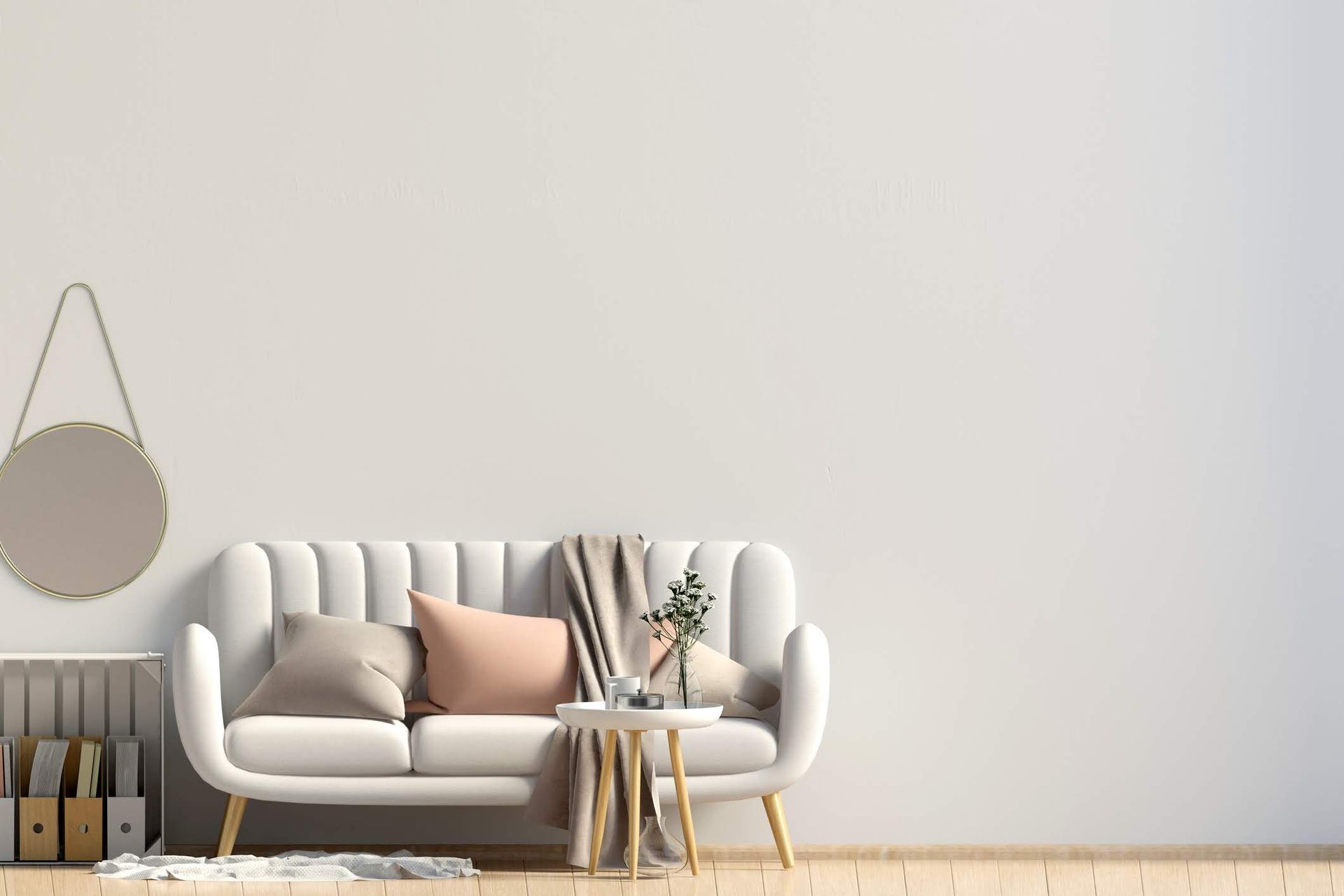 Accogliente soggiorno con divano bianco, cuscini rosa e beige, specchio rotondo e tavolino laterale.