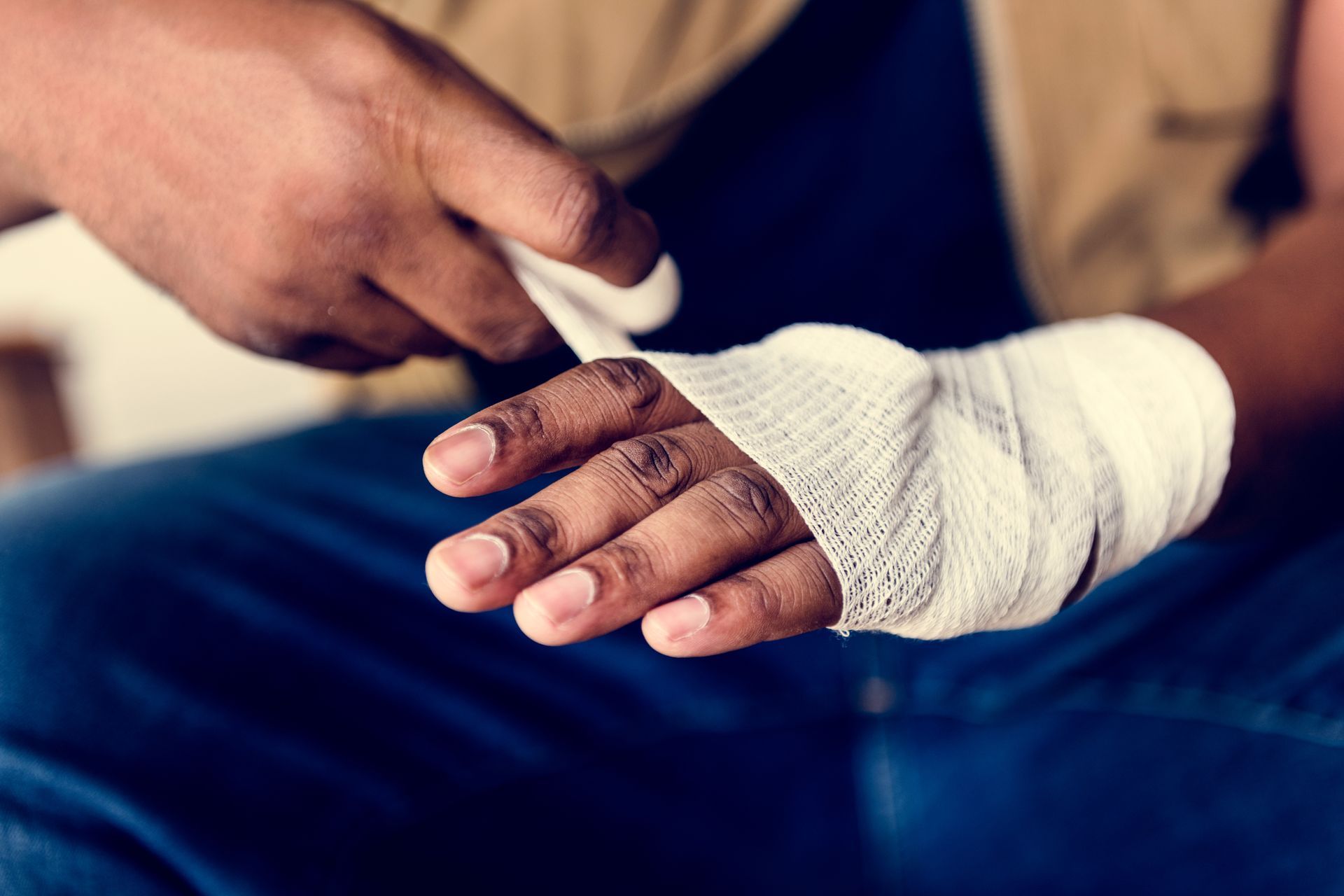 A person in a light blue sweater wears a foam neck brace and holds their neck with a pained expression in an office.