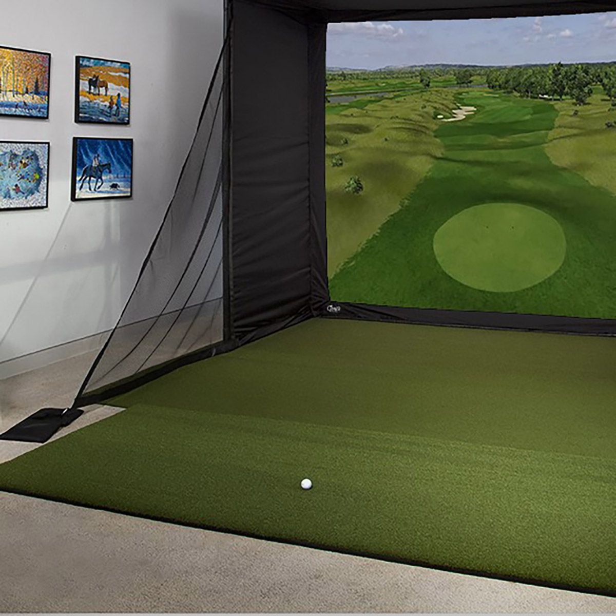 Golf simulator setup in a garage. White screen and net, black sides, green turf, golf balls, and launch monitor.