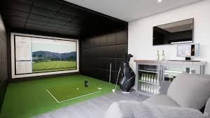 Golf simulator room with a screen displaying a course, putting green, golf clubs, and a bar area.