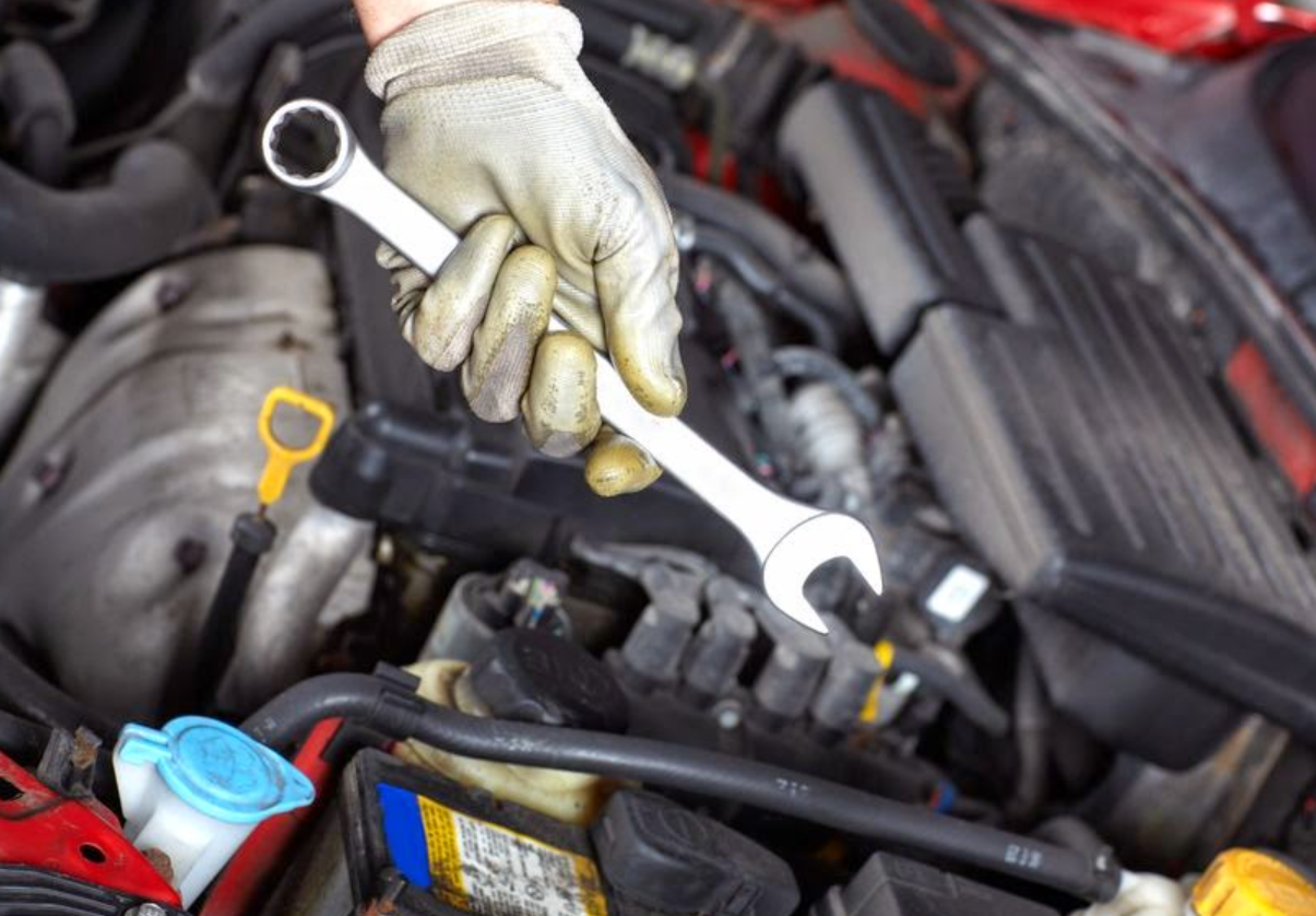 A person is working on a car engine with a wrench.