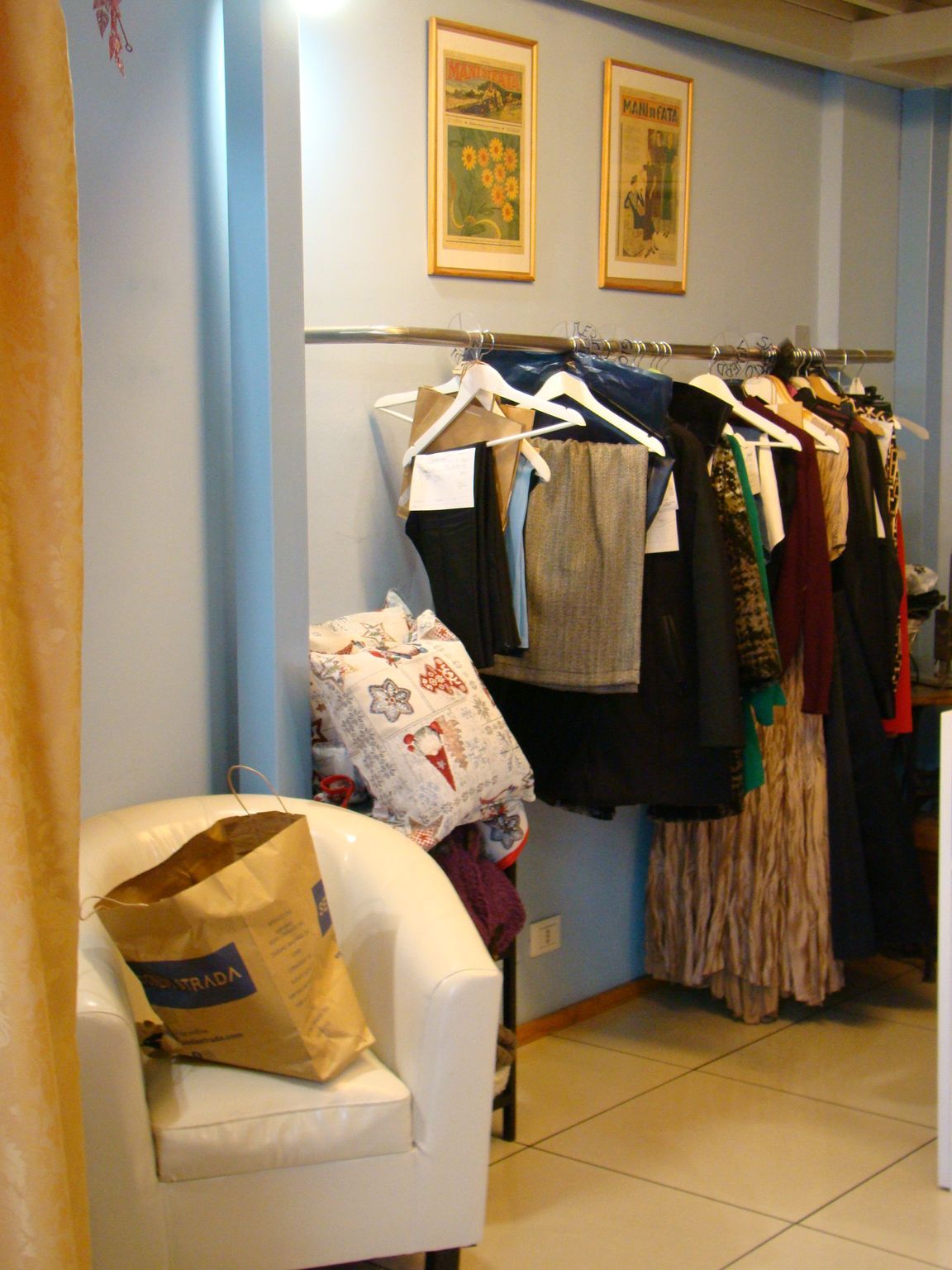 Una stanza con vestiti appesi su grucce e una sedia con una borsa con la scritta Reebok sopra