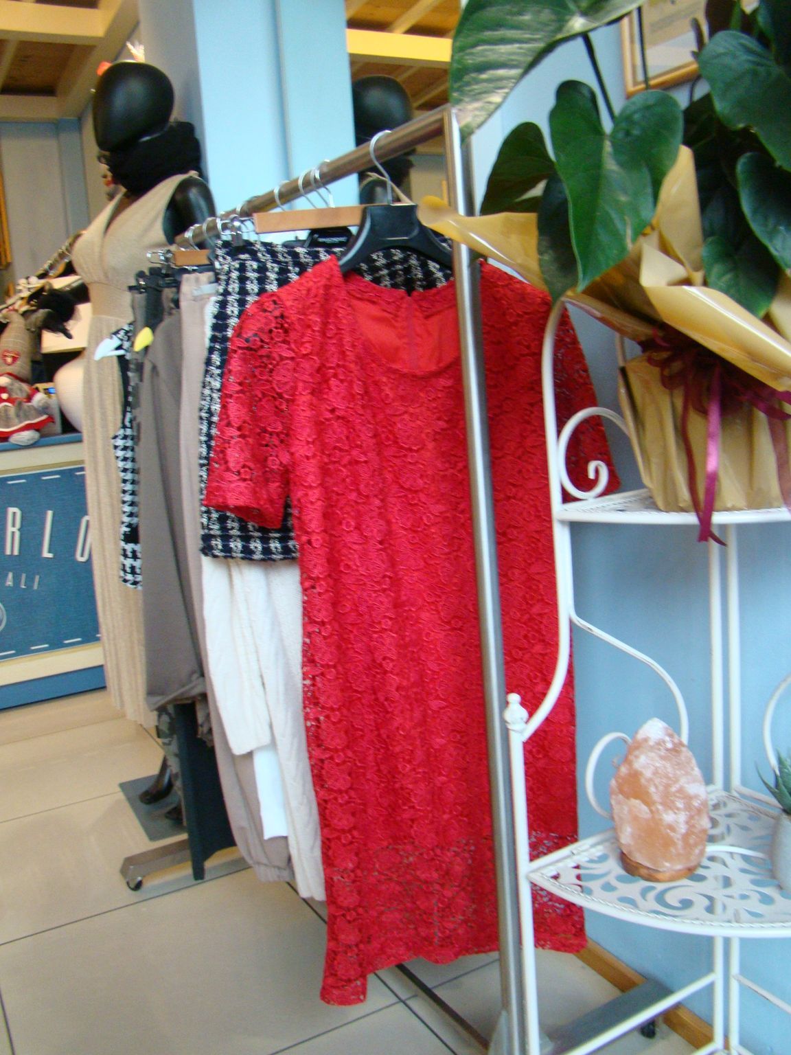 Un vestito di pizzo rosso è appeso su uno scaffale in un negozio