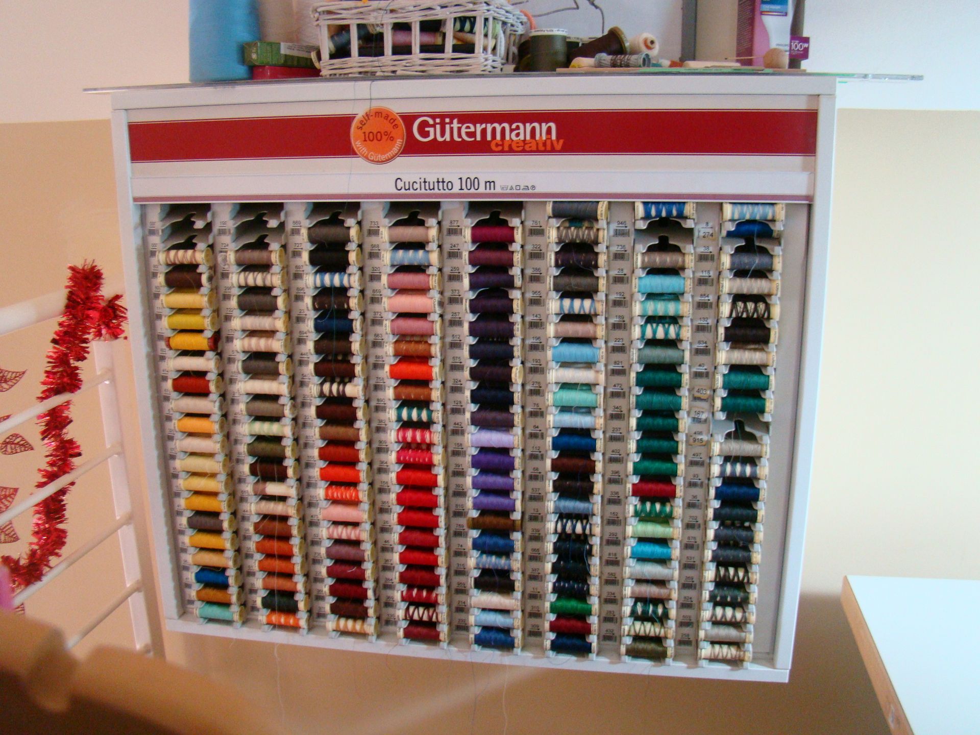 Uno scaffale pieno di rocchetti di filo da cucito con la parola Gutermann sopra