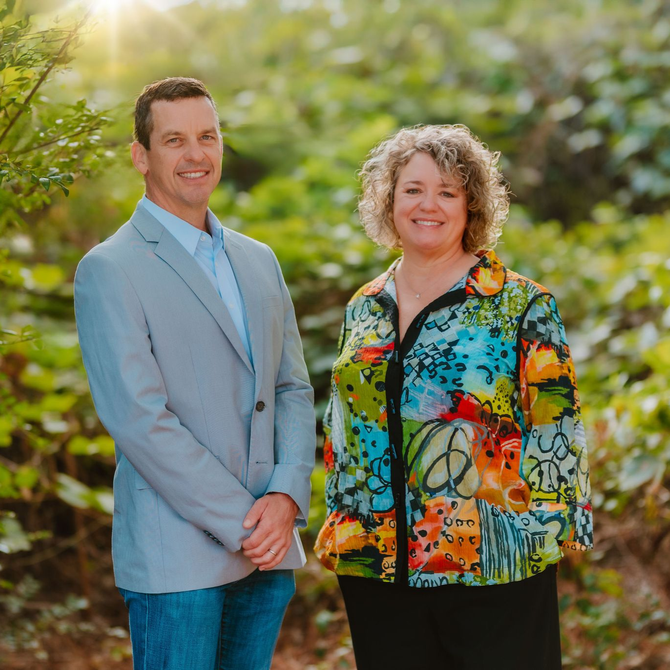 Man in gray jacket and woman in colorful shirt standing outside.