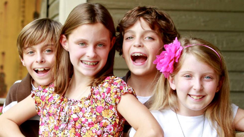 A group of children are posing for a picture together and smiling.