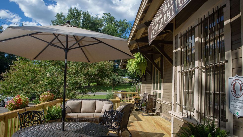 A large umbrella is sitting on a deck next to a couch and chairs.