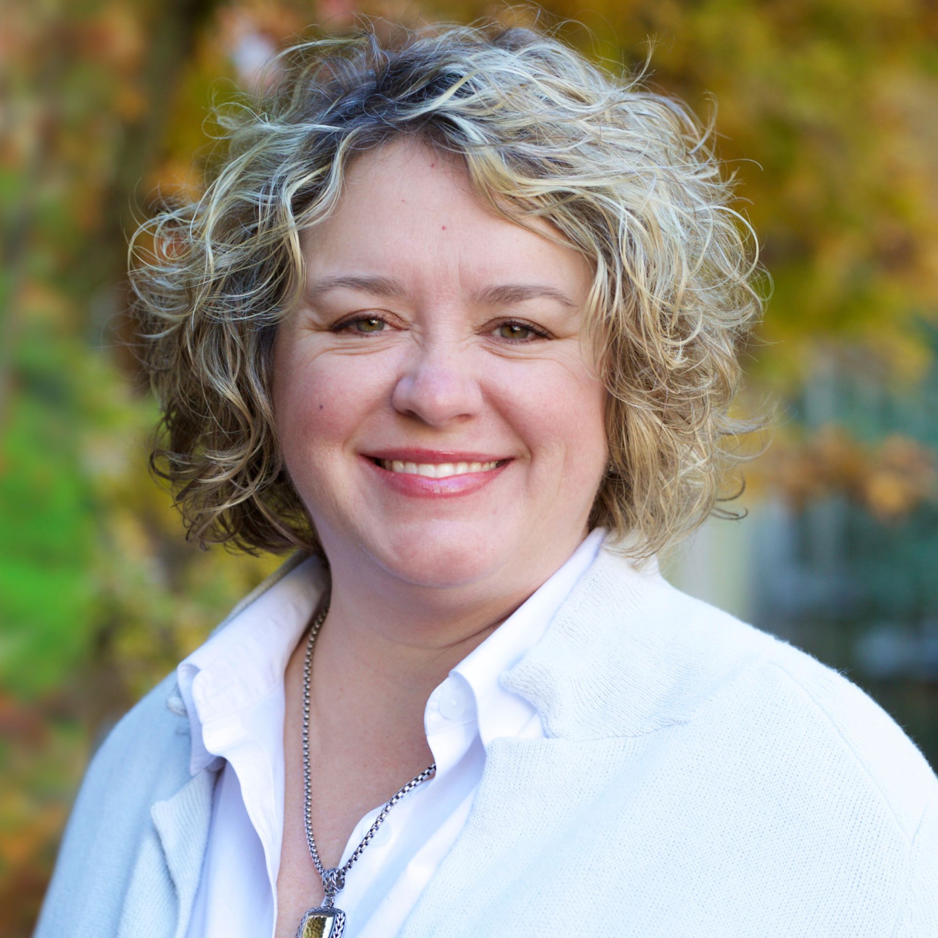 A woman with curly hair is smiling for the camera