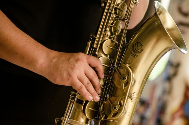 Person playing a golden saxophone, close-up.