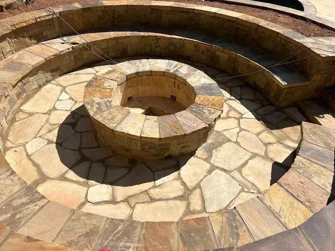 Stone spiral fire pit with tiered seating, outdoors.
