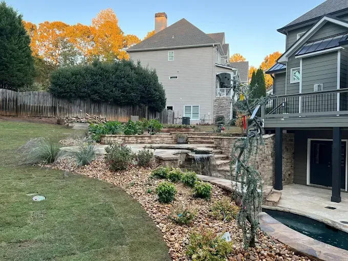Backyard with tiered stone landscaping, small waterfall, and a swimming pool.