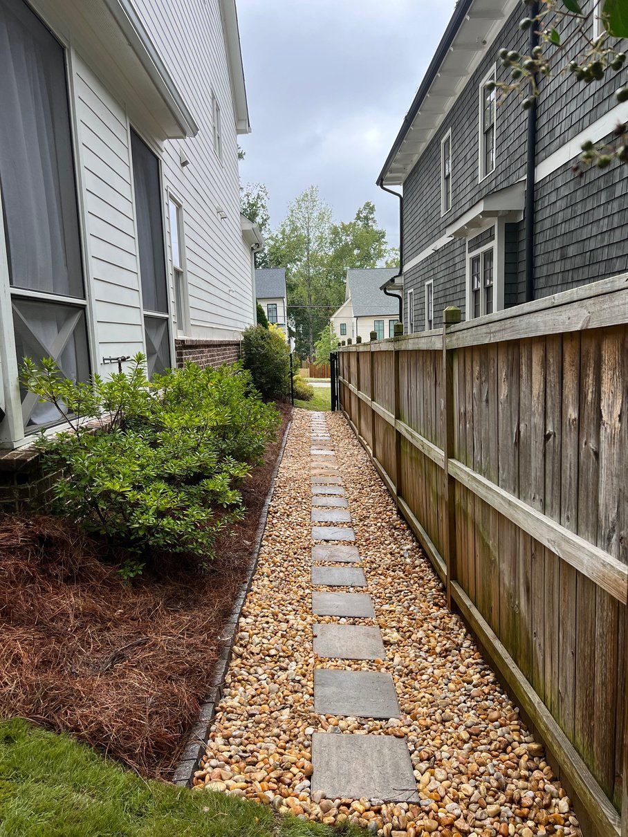 Narrow gravel pathway between two houses, with stepping stones.