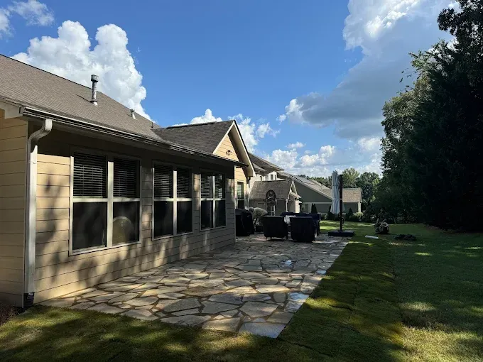 Stone patio outside a house with a green lawn under a blue sky.