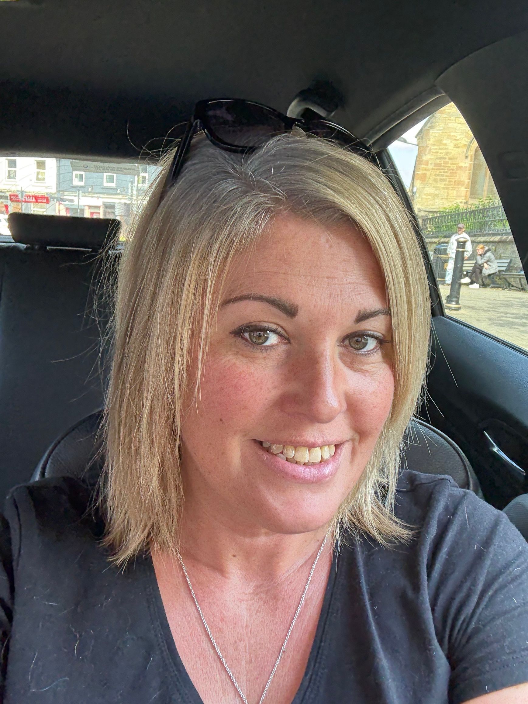 Smiling cartoon woman with wavy brown hair, wearing a purple shirt, and rosy cheeks.